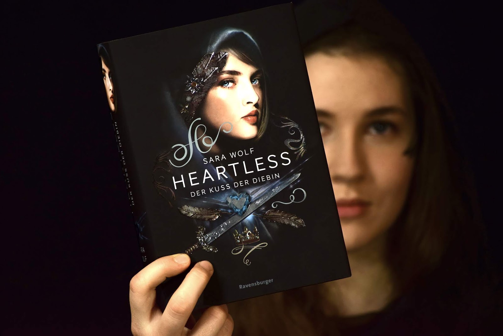 Mila von Das Haus der bunten Bücher posiert mit dem Buch Heartless Der Kuss der Diebin von Sara Wolf